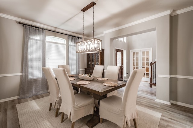 dining area with ornamental molding, light wood-type flooring, and french doors