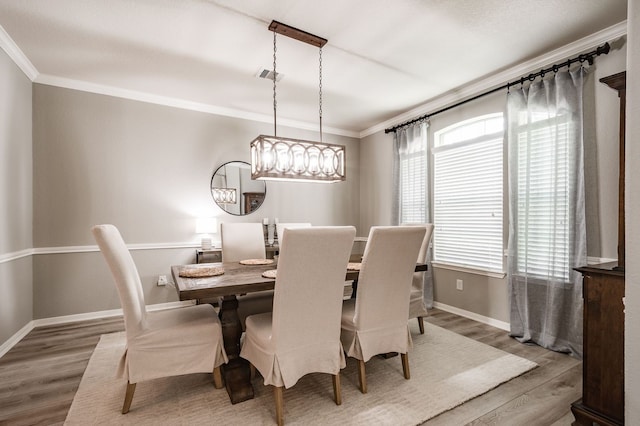 dining area with ornamental molding and hardwood / wood-style flooring