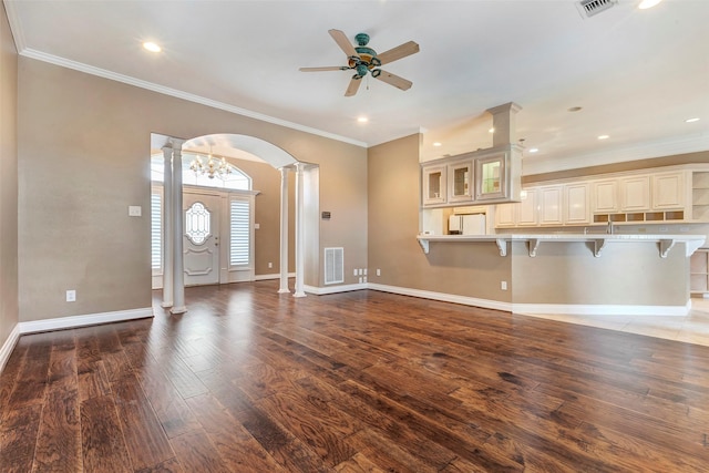 unfurnished living room with ceiling fan with notable chandelier, crown molding, and dark hardwood / wood-style floors