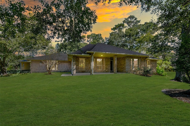 back house at dusk with a patio area and a yard