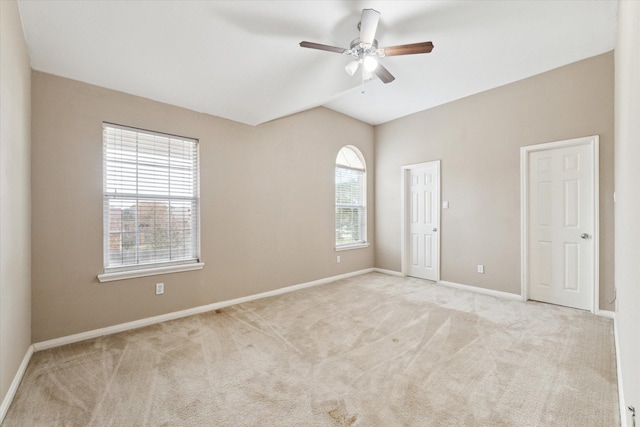 spare room with lofted ceiling, light colored carpet, and ceiling fan