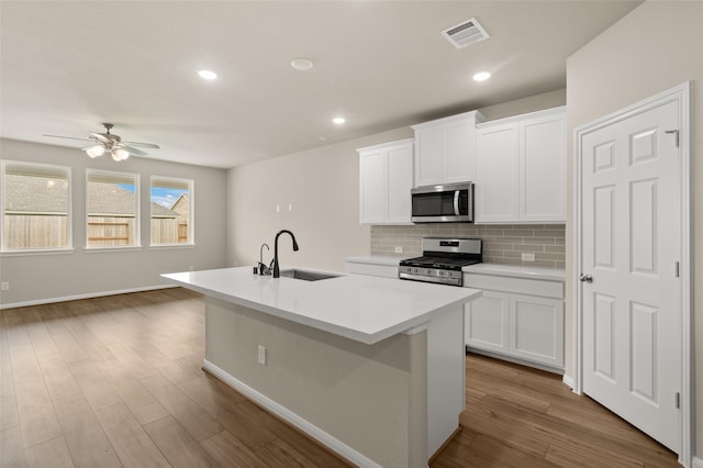 kitchen featuring sink, stainless steel appliances, white cabinetry, and a kitchen island with sink