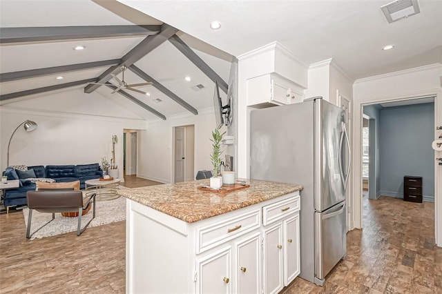 kitchen featuring stainless steel refrigerator, lofted ceiling with beams, ceiling fan, a kitchen island, and white cabinets