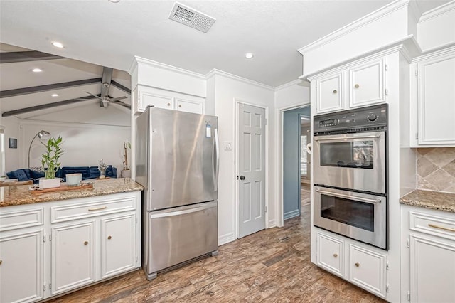 kitchen featuring lofted ceiling with beams, appliances with stainless steel finishes, backsplash, and white cabinetry