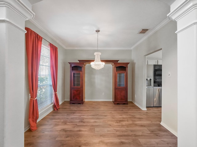 unfurnished dining area featuring an inviting chandelier, light hardwood / wood-style floors, and crown molding