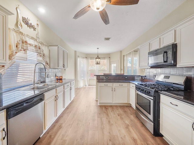 kitchen with appliances with stainless steel finishes, white cabinets, decorative light fixtures, and tasteful backsplash