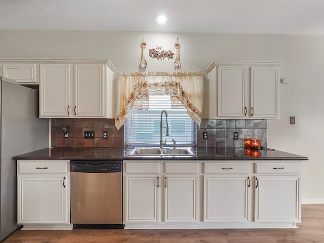 kitchen with stainless steel appliances, sink, white cabinets, light hardwood / wood-style floors, and tasteful backsplash