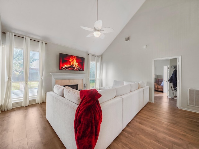 living room featuring a tile fireplace, high vaulted ceiling, ceiling fan, and hardwood / wood-style floors