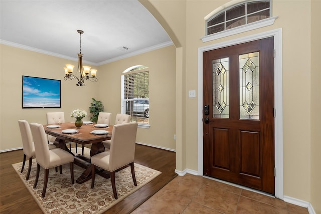 dining space featuring crown molding, tile patterned flooring, and an inviting chandelier