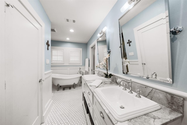 bathroom with tile patterned floors, a tub to relax in, and vanity