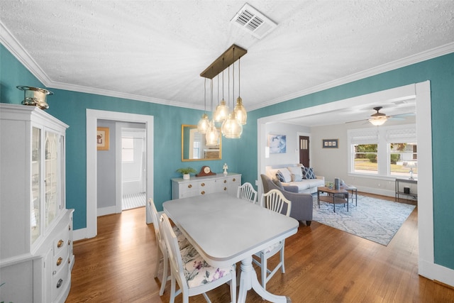 dining room with a textured ceiling, ceiling fan, crown molding, and hardwood / wood-style flooring