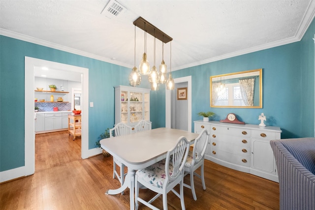 dining room with hardwood / wood-style floors, crown molding, and an inviting chandelier