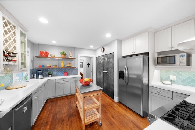 kitchen featuring dark wood-type flooring, backsplash, white cabinets, and stainless steel appliances