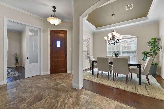 entrance foyer with an inviting chandelier, a tray ceiling, crown molding, and plenty of natural light