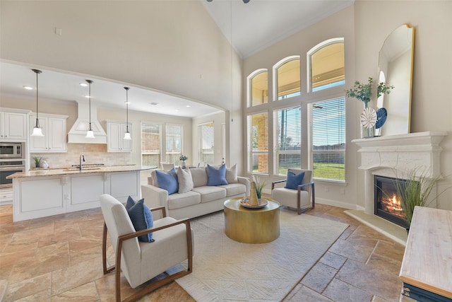 living room with ornamental molding, high vaulted ceiling, and sink