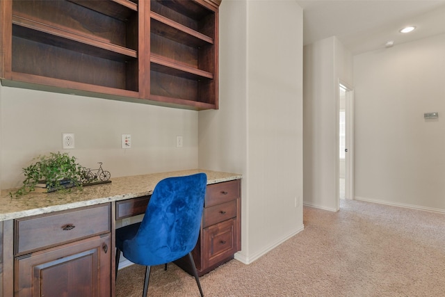 home office with built in desk and light colored carpet