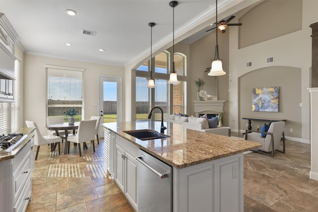 kitchen featuring a center island with sink, appliances with stainless steel finishes, light stone countertops, plenty of natural light, and sink