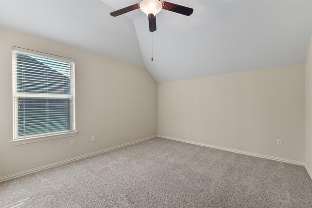 carpeted spare room featuring ceiling fan and vaulted ceiling