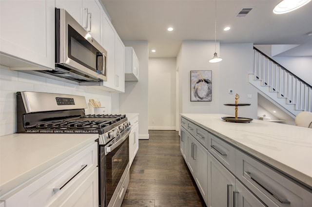 kitchen with stainless steel appliances, light stone countertops, dark hardwood / wood-style flooring, white cabinets, and decorative light fixtures