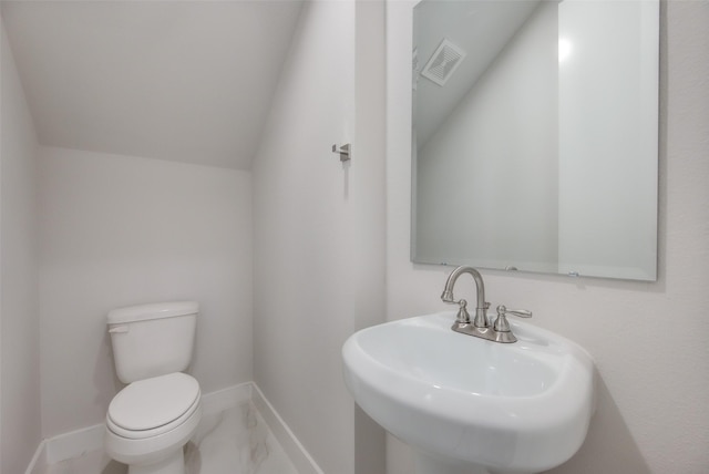 bathroom with toilet, vaulted ceiling, and sink