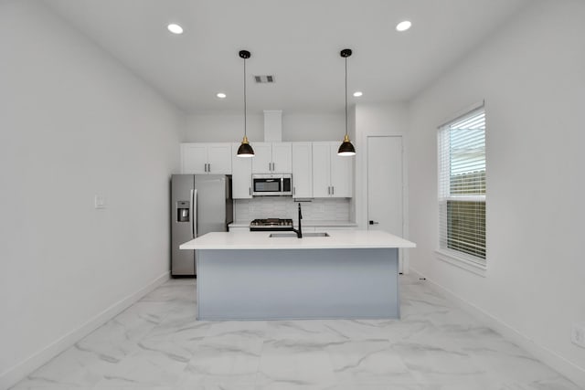 kitchen with appliances with stainless steel finishes, sink, white cabinetry, decorative light fixtures, and tasteful backsplash