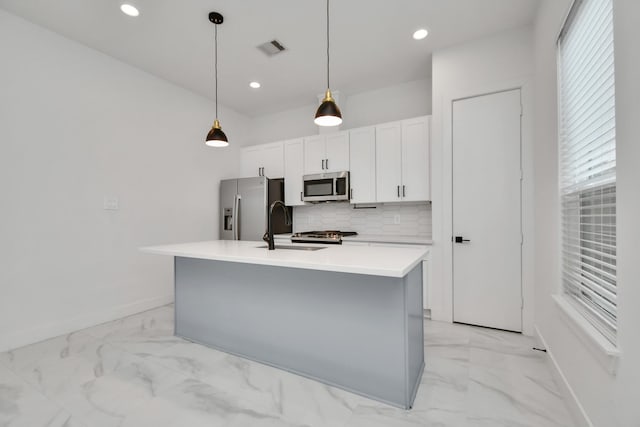 kitchen with pendant lighting, a center island with sink, decorative backsplash, appliances with stainless steel finishes, and sink