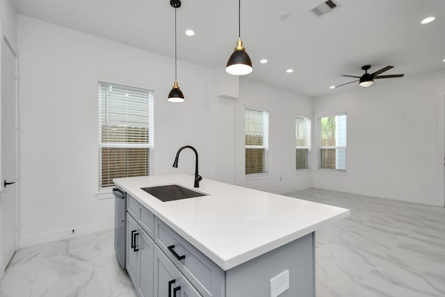 kitchen featuring a healthy amount of sunlight, hanging light fixtures, an island with sink, ceiling fan, and sink