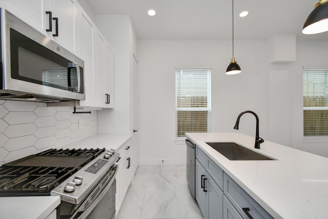 kitchen featuring decorative light fixtures, decorative backsplash, white cabinets, appliances with stainless steel finishes, and sink