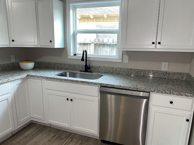 kitchen with stainless steel dishwasher, white cabinetry, sink, and light stone counters