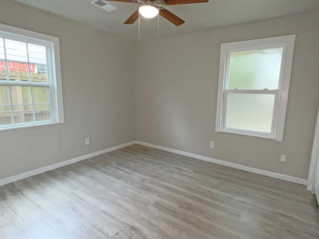 empty room with ceiling fan and light hardwood / wood-style flooring