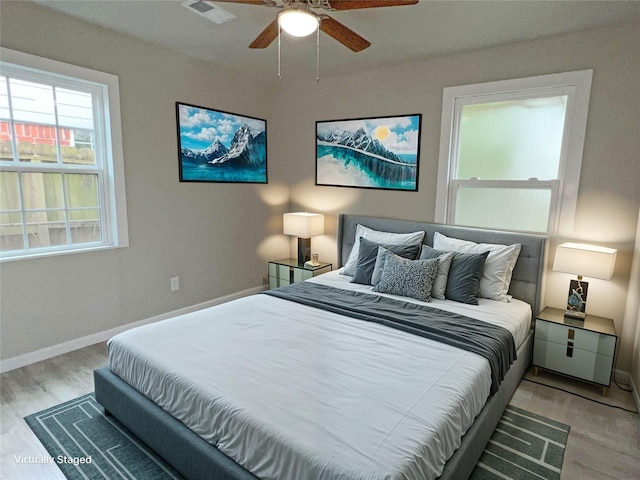 bedroom featuring light wood-type flooring, ceiling fan, and multiple windows