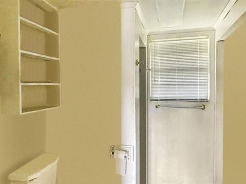 bathroom with toilet, ornamental molding, and built in shelves