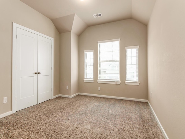 unfurnished bedroom with lofted ceiling, a closet, and carpet