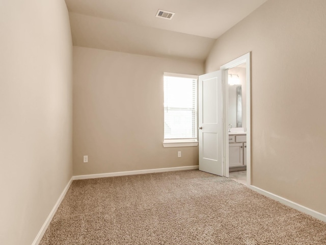 unfurnished bedroom with lofted ceiling, ensuite bath, and light carpet