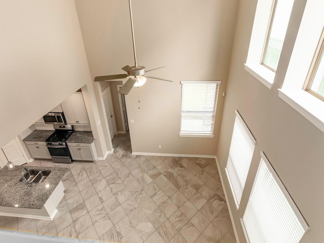 unfurnished living room with a towering ceiling, ceiling fan, and sink