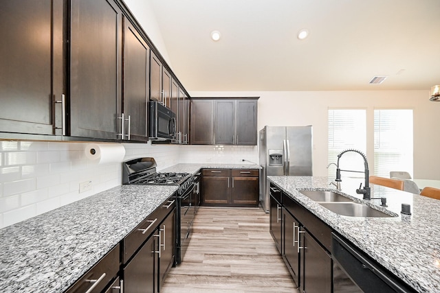 kitchen featuring sink, light stone countertops, backsplash, dark brown cabinetry, and black appliances