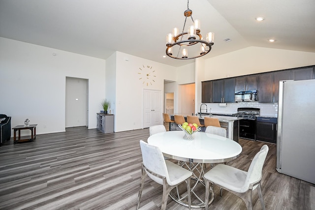 dining space with sink, high vaulted ceiling, an inviting chandelier, and dark wood-type flooring