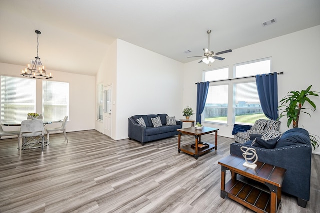 living room with ceiling fan with notable chandelier and light hardwood / wood-style floors