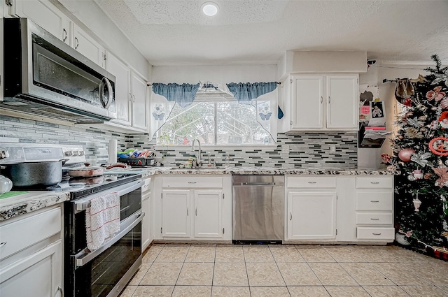 kitchen with stainless steel appliances, sink, a textured ceiling, white cabinetry, and light tile patterned floors