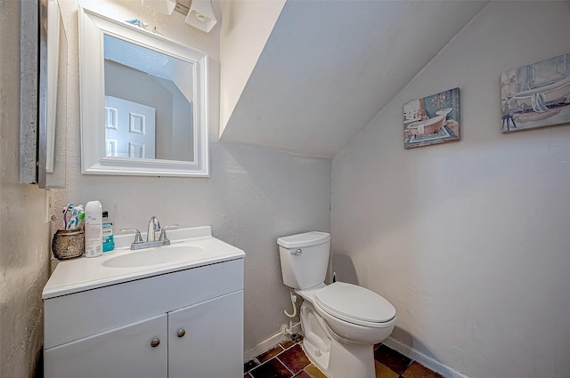 bathroom with tile patterned flooring, vaulted ceiling, vanity, and toilet