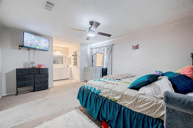 carpeted bedroom featuring ceiling fan, ensuite bathroom, and a textured ceiling