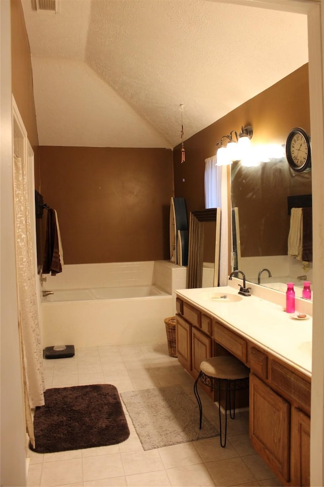 bathroom featuring lofted ceiling, a bathtub, vanity, tile patterned floors, and a textured ceiling