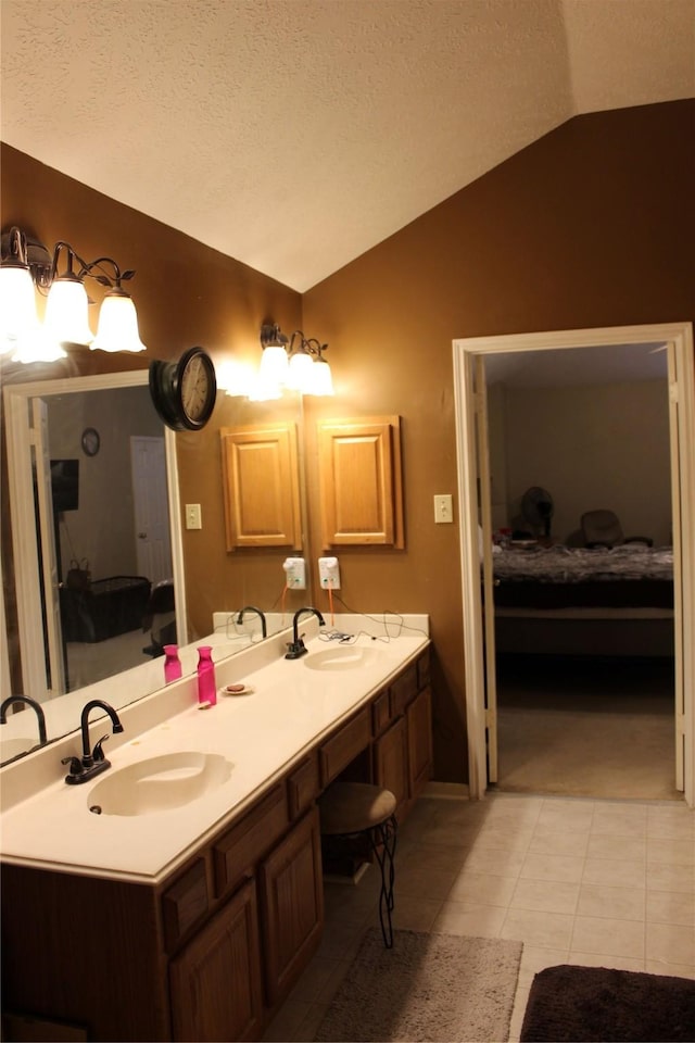 bathroom featuring lofted ceiling, vanity, tile patterned flooring, and a textured ceiling