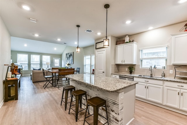 kitchen with decorative light fixtures, sink, white cabinetry, and a center island