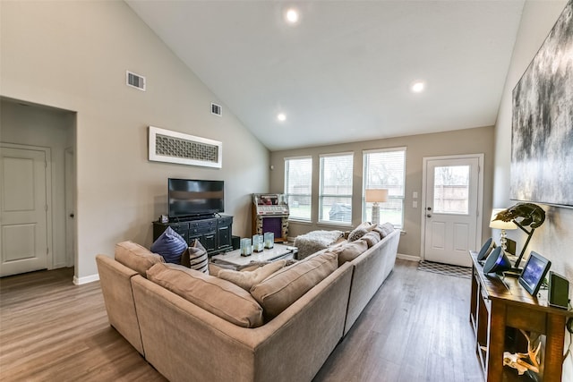 living room with lofted ceiling, a healthy amount of sunlight, a fireplace, and light hardwood / wood-style floors