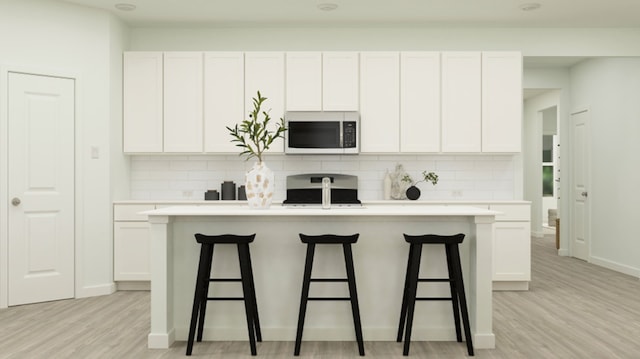 kitchen with white cabinets, range, and a center island with sink