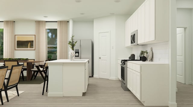 kitchen featuring light hardwood / wood-style flooring, a center island with sink, a kitchen bar, white cabinetry, and appliances with stainless steel finishes