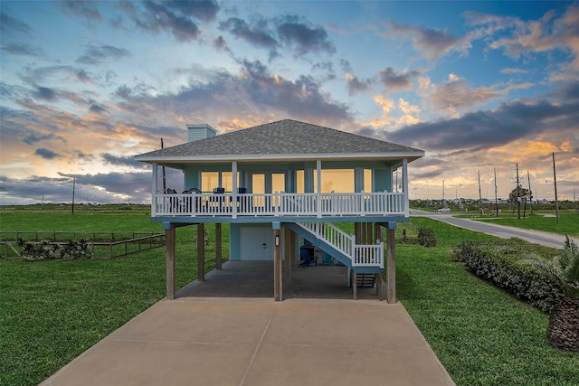 beach home featuring covered porch, a lawn, and a garage