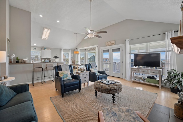 living room with a textured ceiling, ceiling fan, and light hardwood / wood-style floors