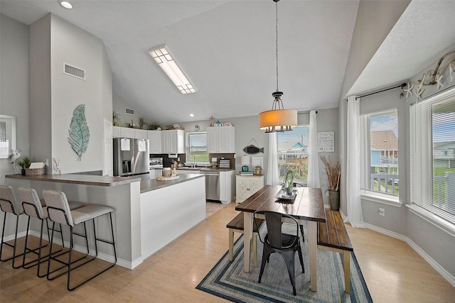 kitchen with stainless steel appliances, white cabinetry, a kitchen breakfast bar, kitchen peninsula, and pendant lighting